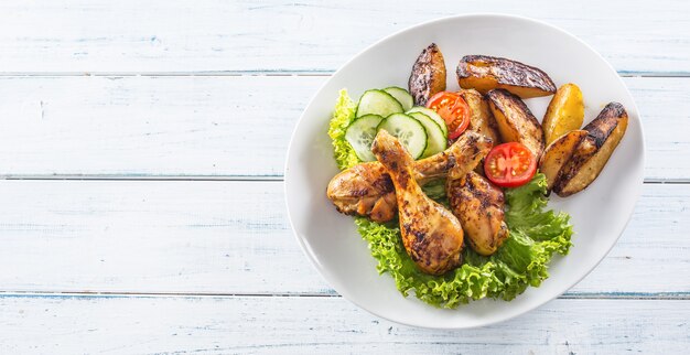 Roasted chicken legs with lettuce salad and tomatoes.