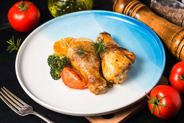 Foto cosce di pollo arrosto con verdure ed erbe aromatiche