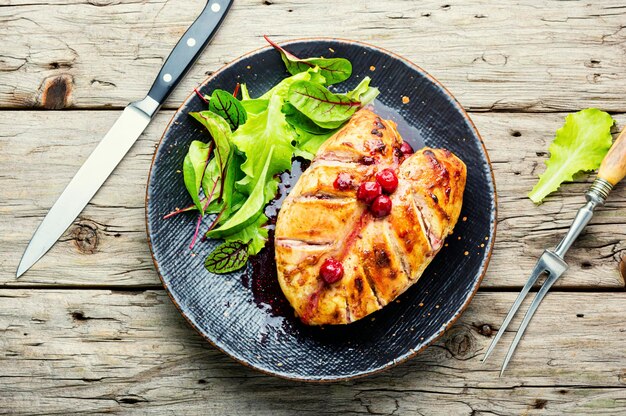 Roasted chicken meat and cherry sauce for the meat on retro wooden table