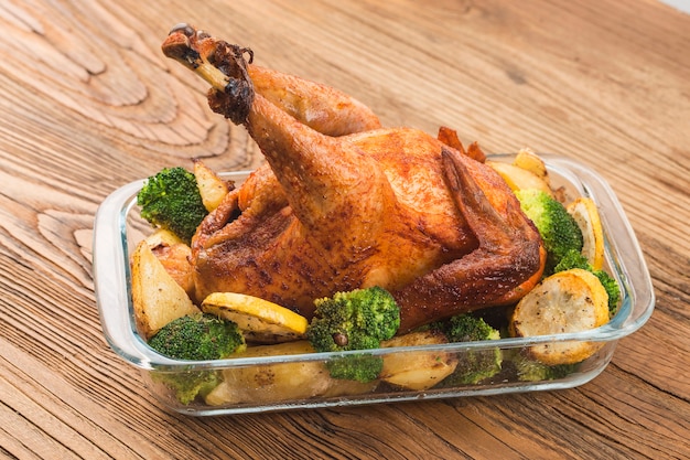 жареный цыпленок и овощи на деревянном столе