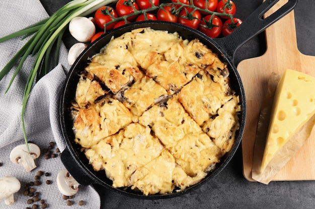 Photo roasted chicken with cheese in frying pan on kitchen table