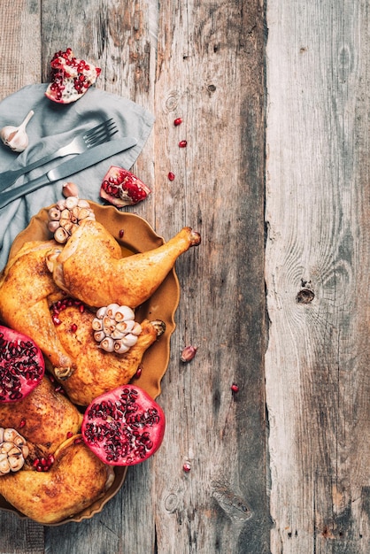 Roasted chicken with pomegranate and garlic on wooden background Friends or family dinner Festive Christmas table Top view Traditional Thanksgiving or Friendsgiving holiday celebration dish