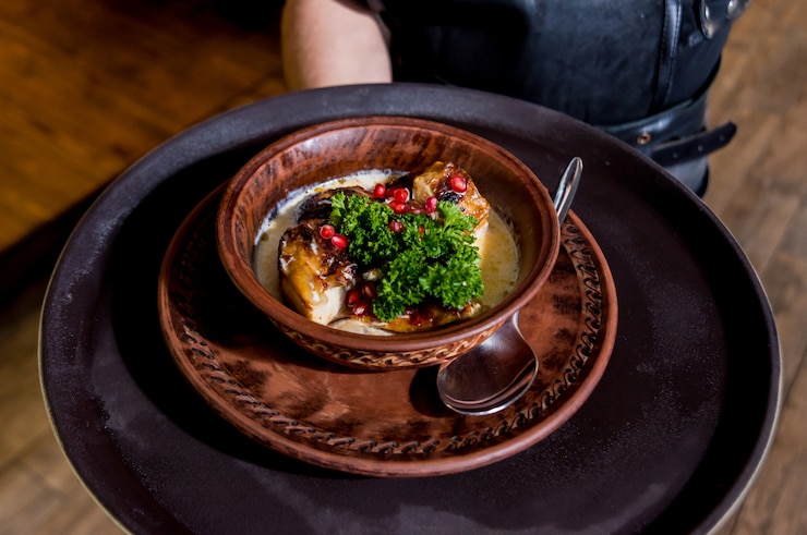 Фотография жареная курица с картофелем и овощами на кухонной плите.