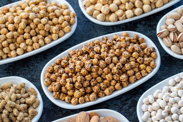 Roasted chickpeas in selective focus Nuts on plate on a dark background Walnut Chickpeas White Chickpeas Dry mulberry almond cashew pistachio Types of nuts on the plate