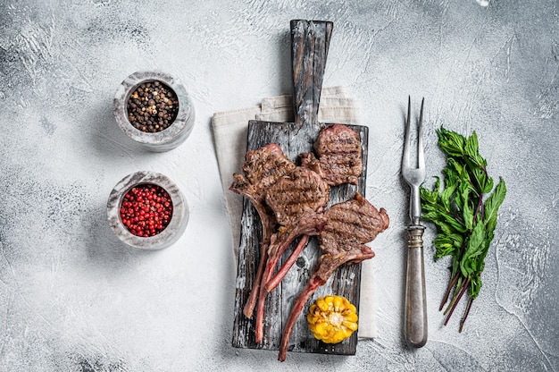 Photo roasted chops steaks of  lamb mutton on a wooden board. white background. top view.