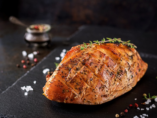 Roasted Christmas ham of turkey on dark rustic background.  Festival food.