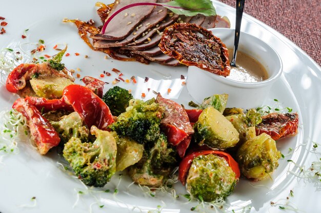 Roasted cod fillets rolls served with millet and steamed broccoli, carrot, brussels sprouts and zucchini