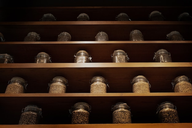 Жареные кофейные зерна в стеклянной коробке на деревянной полке