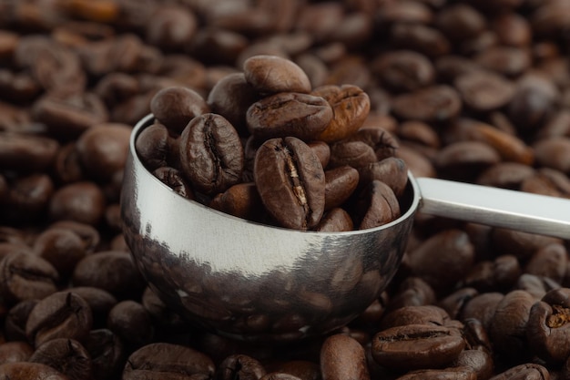 Foto chicco di caffè arrostito in cucchiaio con fumo.