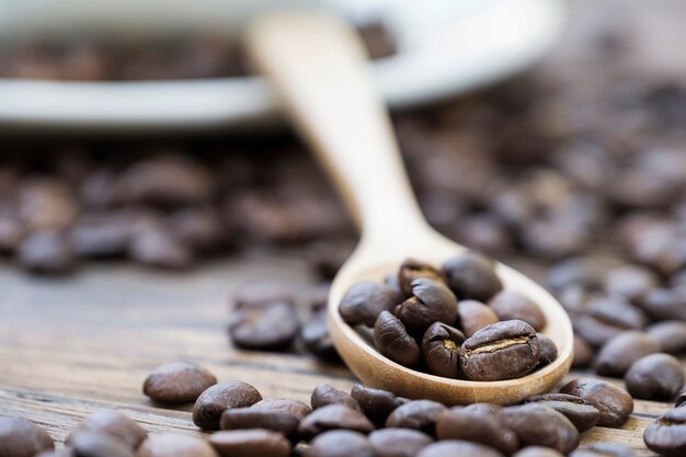 Foto chicco di caffè arrostito in cucchiaio di legno circondato dal chicco di caffè