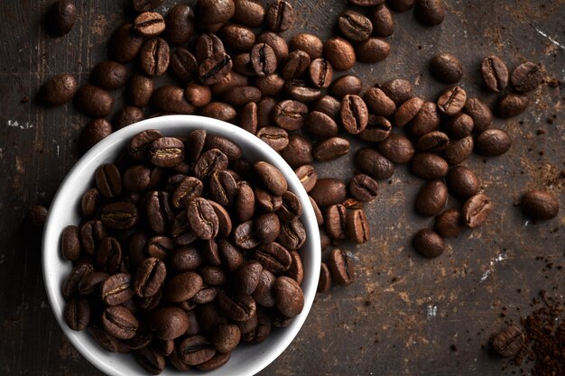 Roasted coffee beans in bowl isolated close up on brown grunge background