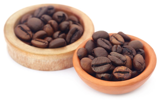 Roasted coffee beans in bowls over white background