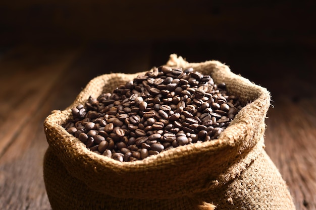 삼베 자루에 볶은 커피 콩 삼 베 자루에 갓 볶은 강한 향기로운 짙은 갈색 커피 콩 이 사진은 연기와 함께 사용할 수 있습니다.