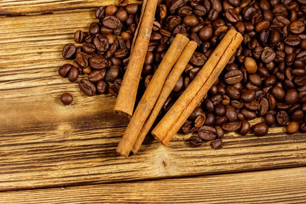 Roasted coffee beans and cinnamon sticks on rustic wooden background. Top view