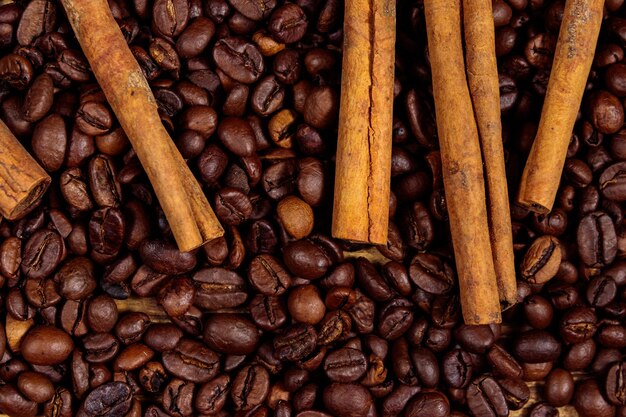 Roasted coffee beans and cinnamon sticks on rustic wooden background. Top view