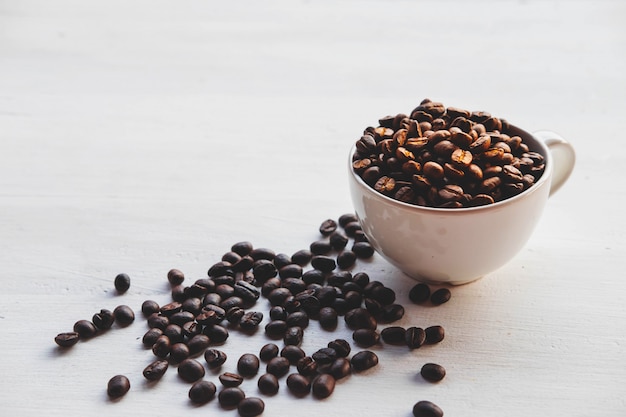 Roasted coffee beans in a coffee cup on a white background