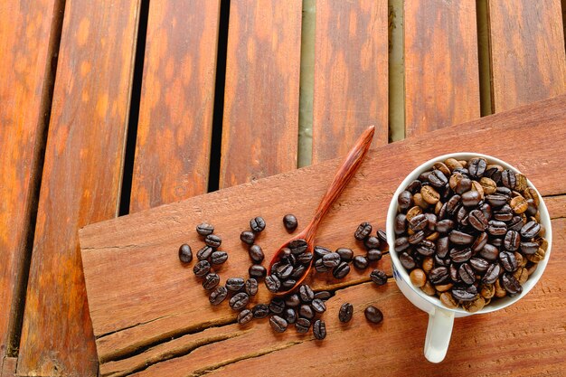 Roasted coffee beans in a cup of coffee on a wooden table.