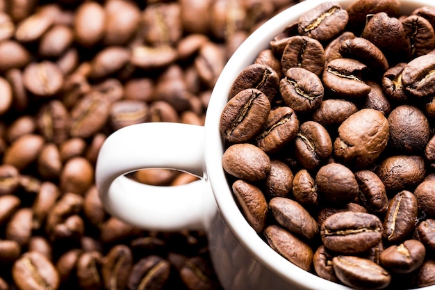 Roasted coffee beans in a cup on dark background closeup image space for text