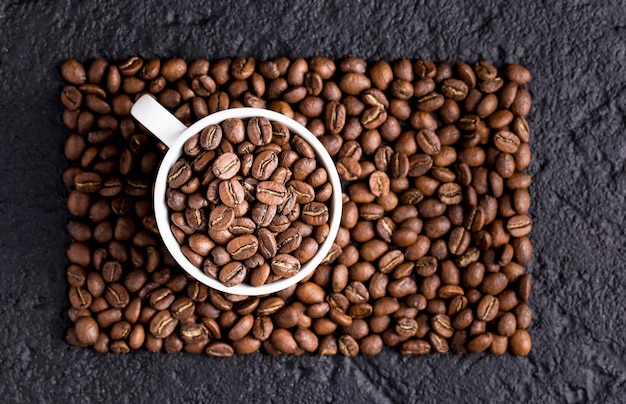 Roasted coffee beans in a cup on dark background closeup image space for text