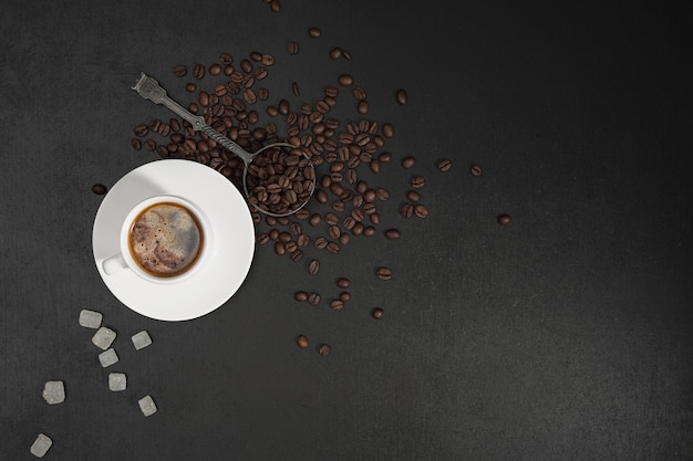 Roasted coffee beans and cup of hot espresso coffee. Top view flat lay with copy space