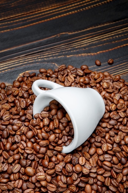 Roasted coffee beans and cup on wooden background