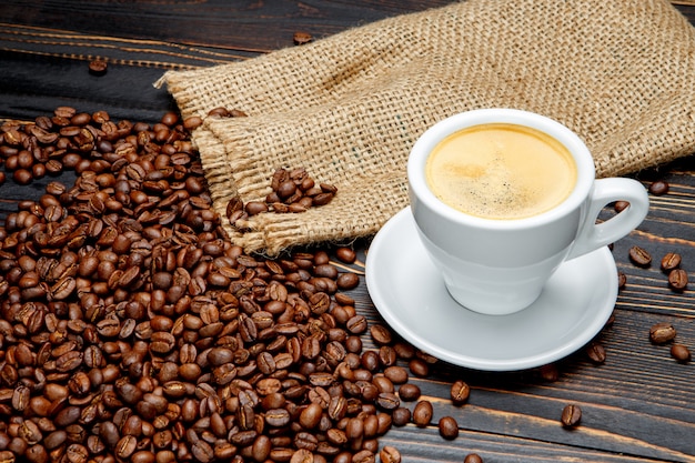 Roasted coffee beans and cup on wooden background