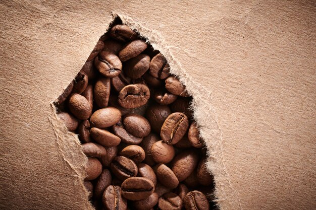 Roasted coffee beans decorated with kraft paper closeup creative background