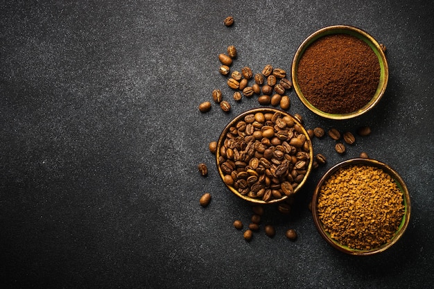 Roasted coffee beans ground coffee and instant coffee in bowls at dark background Top view image