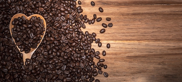 Roasted coffee beans and heart spoon On wooden background