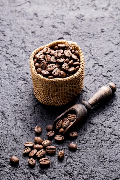Фото Жареные кофейные зерна в тканевом мешке на темном фоне крупным планом пространство изображения для текста