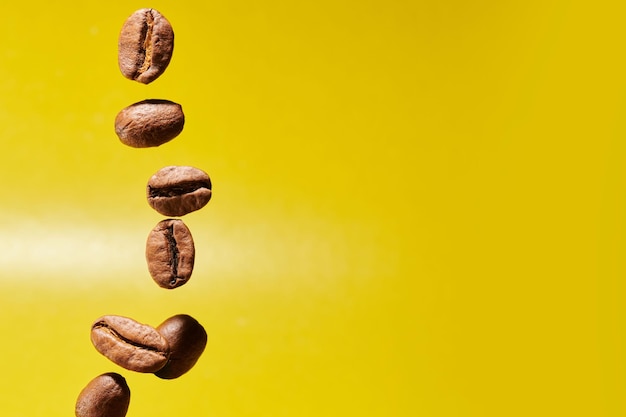 Roasted coffee beans isolated close up on yellow background clipping path