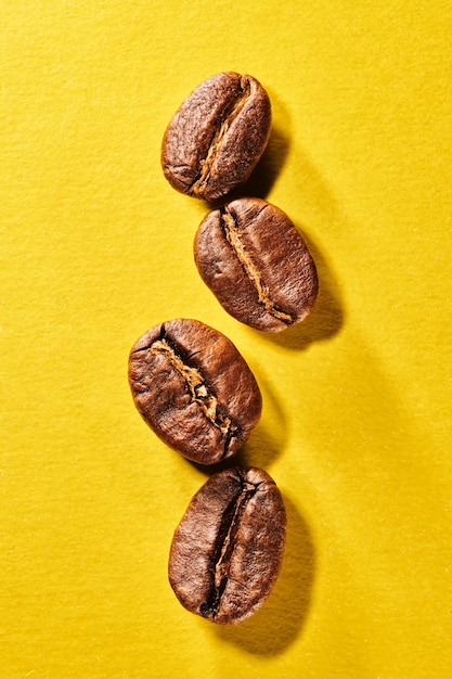 Roasted coffee beans isolated close up on yellow background clipping path