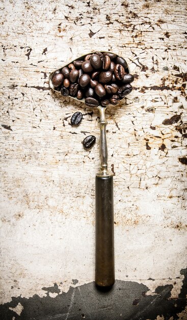 Foto chicchi di caffè tostati nel vecchio cucchiaio sul tavolo rustico.