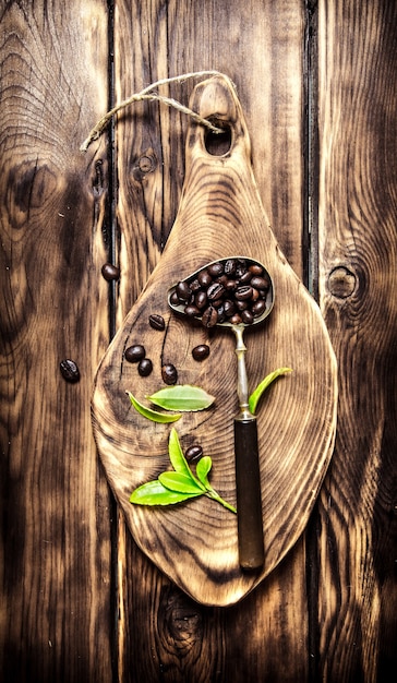 Chicchi di caffè tostati nel vecchio cucchiaio su una tavola di legno. sullo sfondo di legno.