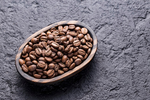 Roasted coffee beans on a plate on a dark background closeup image space for text