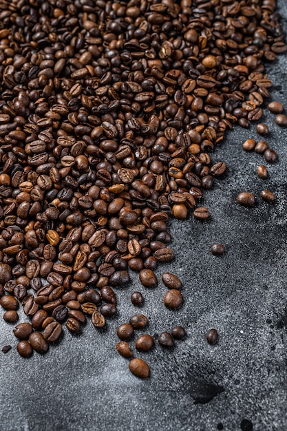 Chicchi di caffè tostati sulla tavola rustica. sfondo nero. vista dall'alto.