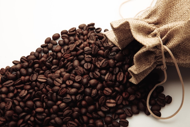 袋のクローズアップに散らばった焙煎コーヒー豆。