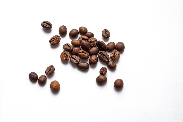 Photo roasted coffee beans scattered on white surface