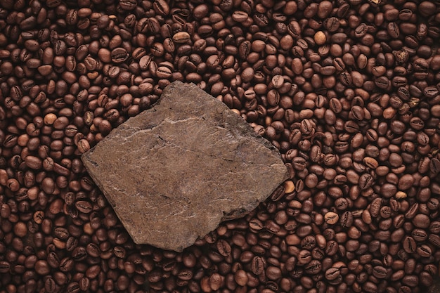 Roasted coffee beans on stone pedestal brown background