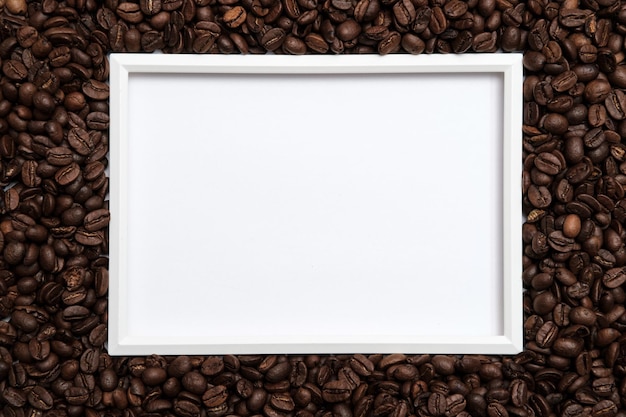 Roasted coffee beans surround a frame on a white background Copy space Top view