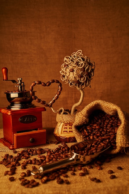 Roasted coffee beans, vintage coffee-mill on sacking background