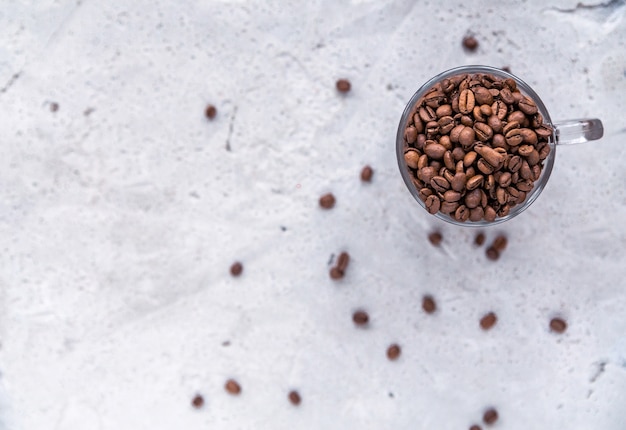 Roasted coffee beans in white cup.  Light concrete background. Top view. Horizontal photo