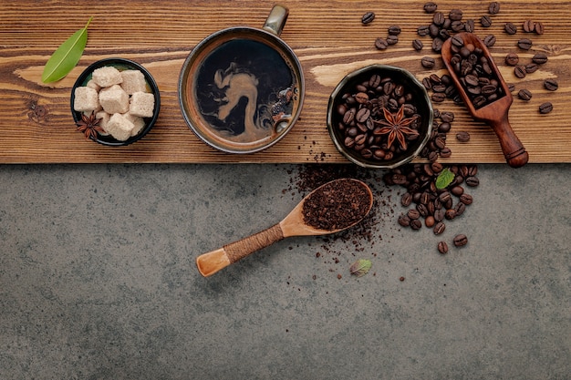 Roasted coffee beans with coffee cup setup on dark stone background.
