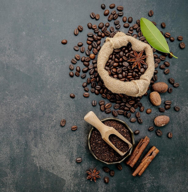 어두운 돌 배경에 맛있는 커피를 만들기 위해 커피 가루와 풍미 있는 재료를 곁들인 볶은 커피 콩