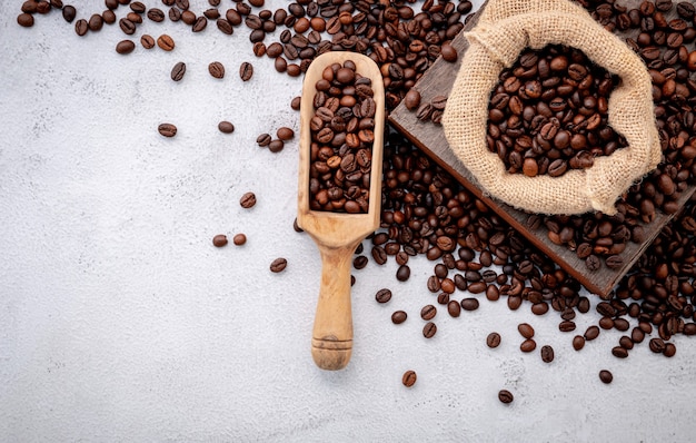 Roasted coffee beans with scoops setup on white concrete.