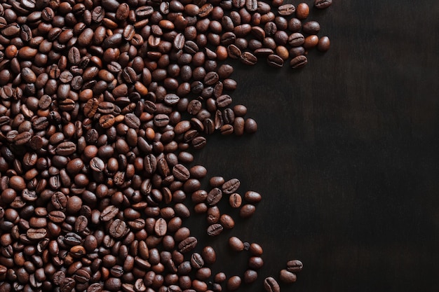 Roasted coffee beans on a wooden dark table top view copy space Place for text