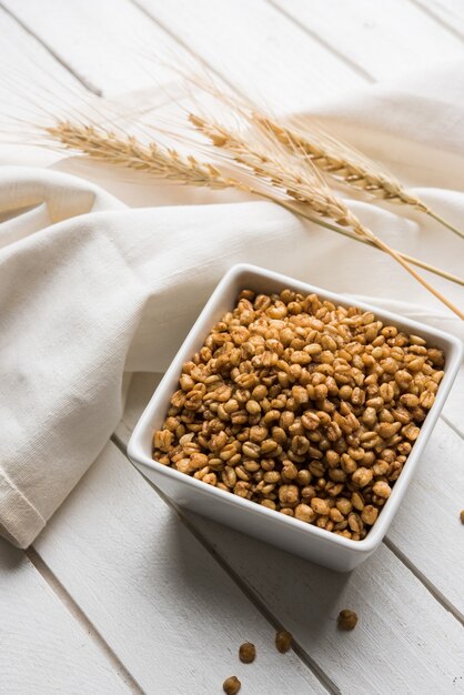 Roasted Crunchy Wheat - Indian Dietary Supplement, served in a white bowl over moody background, selective focus