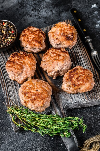 Roasted cutlets from beef and pork meat. Black background. Top view.