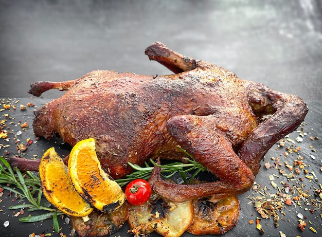 Roasted duck in a smoker grill on dark background Copy space
