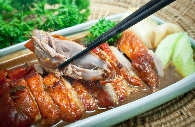 Roasted duck with sauce and vegetables holded with chopsticks